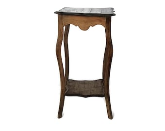 Puede incluir: Un pequeño y antiguo soporte de madera para plantas con acabado marrón oscuro. El soporte presenta una parte superior festoneada y un estante inferior, sostenido por patas curvas. El soporte mide aproximadamente 76 cm de altura.