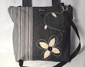 Large tote bag made of lined navy denim, with genuine leather flower pattern. Handles and adjustables shoulder strap.