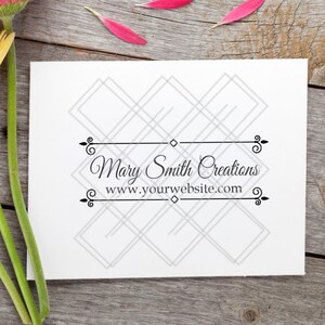 May include: A white card with the text "Mary Smith Creations" and "www.yourwebsite.com" is displayed on a wooden surface. Three gerbera daisies in shades of orange, yellow, and pink are arranged near the card.