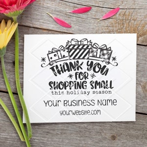 May include: A white card with the text "THANK YOU FOR SHOPPING SMALL this holiday season" and "Your Business Name yourwebsite.com" is next to three colorful gerbera daisies. The flowers are orange, yellow, and pink.