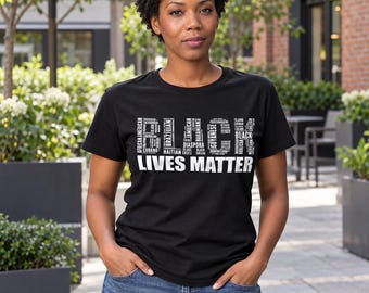 Puede incluir: Una camiseta negra de manga corta con texto blanco que dice BLACK LIVES MATTER, donde la palabra BLACK está compuesta por varias identidades culturales como African American, Brazilian, Jamaican y Haitian.