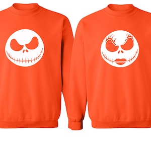 Puede incluir: Dos sudaderas de color naranja con caras blancas de Jack Skellington y Sally de la pel&iacute;cula Pesadilla antes de Navidad.