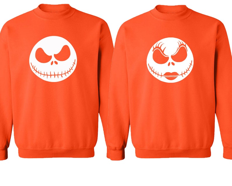 Puede incluir: Dos sudaderas de color naranja con caras blancas de Jack Skellington y Sally de la pel&iacute;cula Pesadilla antes de Navidad.