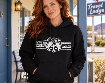 Puede incluir: Una sudadera negra con capucha y un estampado gráfico blanco en el pecho. El diseño muestra un emblema en forma de escudo con el texto Route US 66, flanqueado por las palabras Get Your y Kicks, todo en un estilo desgastado y envejecido.