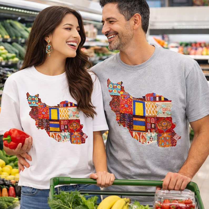 May include: A woman and a man wearing matching t-shirts with a colorful patchwork design in the shape of a country. The woman's shirt is white, and the man's is gray. They are smiling and standing in a grocery store.