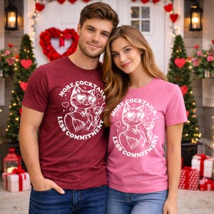 Może przedstawiać: Dwie osoby w pasujących koszulkach. Bordowe i różowe koszulki przedstawiają kota w okularach przeciwsłonecznych w kształcie serca i koktajl z napisem "More Cocktails, Less Commitment".