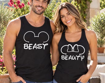 May include: Two black tank tops featuring white graphic prints. One tank top displays a mouse ear outline above the text BEAST. The other tank top features a mouse ear outline with a bow above the text BEAUTY. Both are sleeveless shirts.