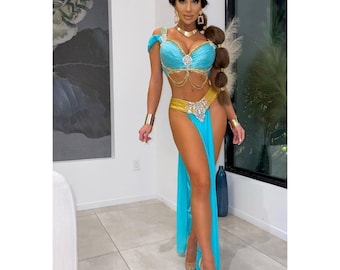 May include: A woman wearing a blue and gold costume with a long, flowing skirt. She is wearing a jeweled headpiece and a gold belt. The costume is reminiscent of a popular Disney princess.