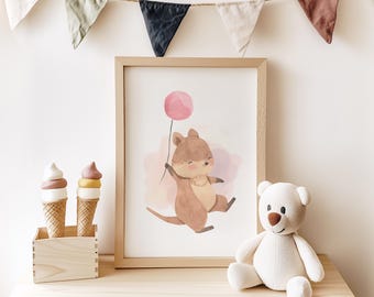 May include: A watercolor print of a brown kangaroo holding a pink balloon. The print is framed in a light brown wood frame and is displayed on a shelf with two ice cream cones and a white teddy bear.