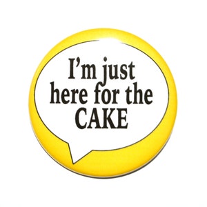 May include: Yellow button with a white speech bubble that says "I'm just here for the CAKE".