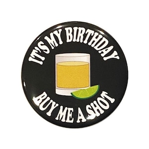 May include: Black and white button with the text "It's My Birthday Buy Me A Shot" in white. A cartoon image of a shot glass with a lime wedge is in the center of the button.