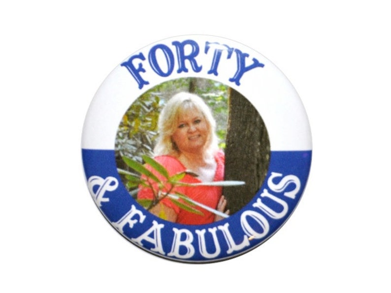 May include: A white button with blue trim and the text "FORTY & FABULOUS" in blue. A photo of a woman is in the center of the button.