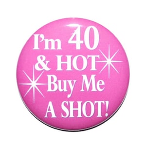 May include: Pink round button with white text that reads "I'm 40 & HOT Buy Me A SHOT!" with a white starburst design.