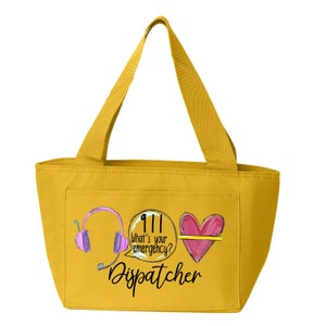 May include: A yellow tote bag with a design featuring a headset, a speech bubble with the text "911 What's your emergency?" and a heart with a yellow line through it. The text "Dispatcher" is printed below the design.