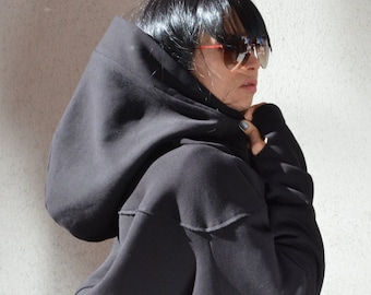 May include: A black hooded sweatshirt with a large hood that can be pulled up over the head. The sweatshirt has long sleeves and a relaxed fit.