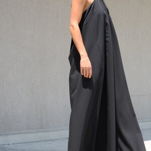 Pu&ograve; includere: Un abito maxi nero con scollo halter e una silhouette fluida. L'abito &egrave; realizzato in un tessuto leggero e ha una vestibilit&agrave; rilassata.