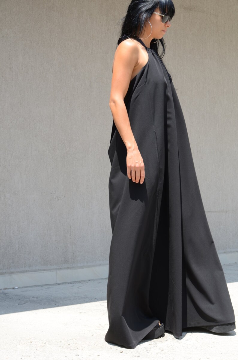 Pu&ograve; includere: Un abito maxi nero con scollo halter e una silhouette fluida. L'abito &egrave; realizzato in un tessuto leggero e ha una vestibilit&agrave; rilassata.