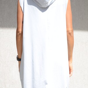 May include: A sleeveless hooded dress in a light gray color. The dress has a loose fit and a long, flowing silhouette.