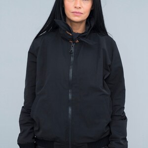 May include: A black zip-up jacket with a high collar and a tied bow detail at the neck.
