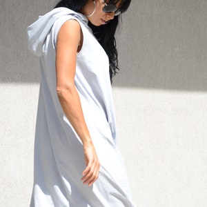 May include: A light gray sleeveless hooded dress with a loose fit. The dress is made of a soft, comfortable fabric and has a relaxed, casual style.