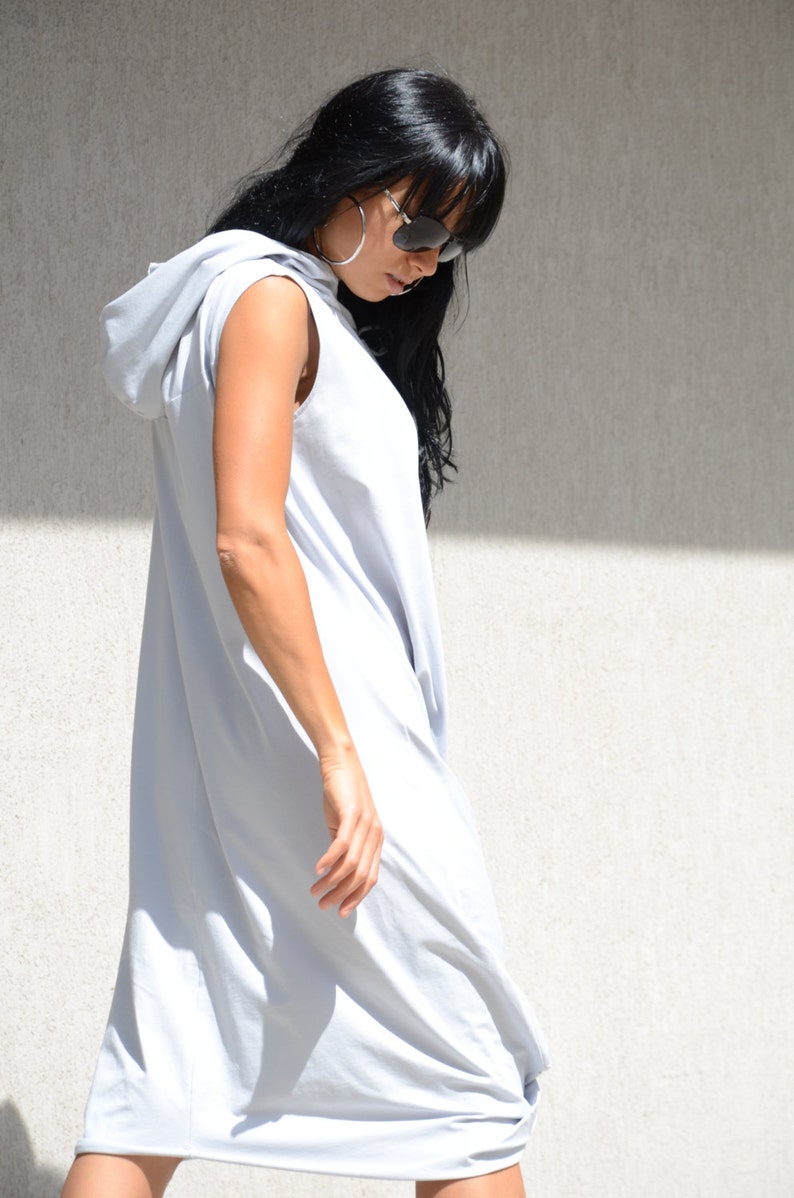 May include: A light gray sleeveless hooded dress with a loose fit. The dress is made of a soft, comfortable fabric and has a relaxed, casual style.
