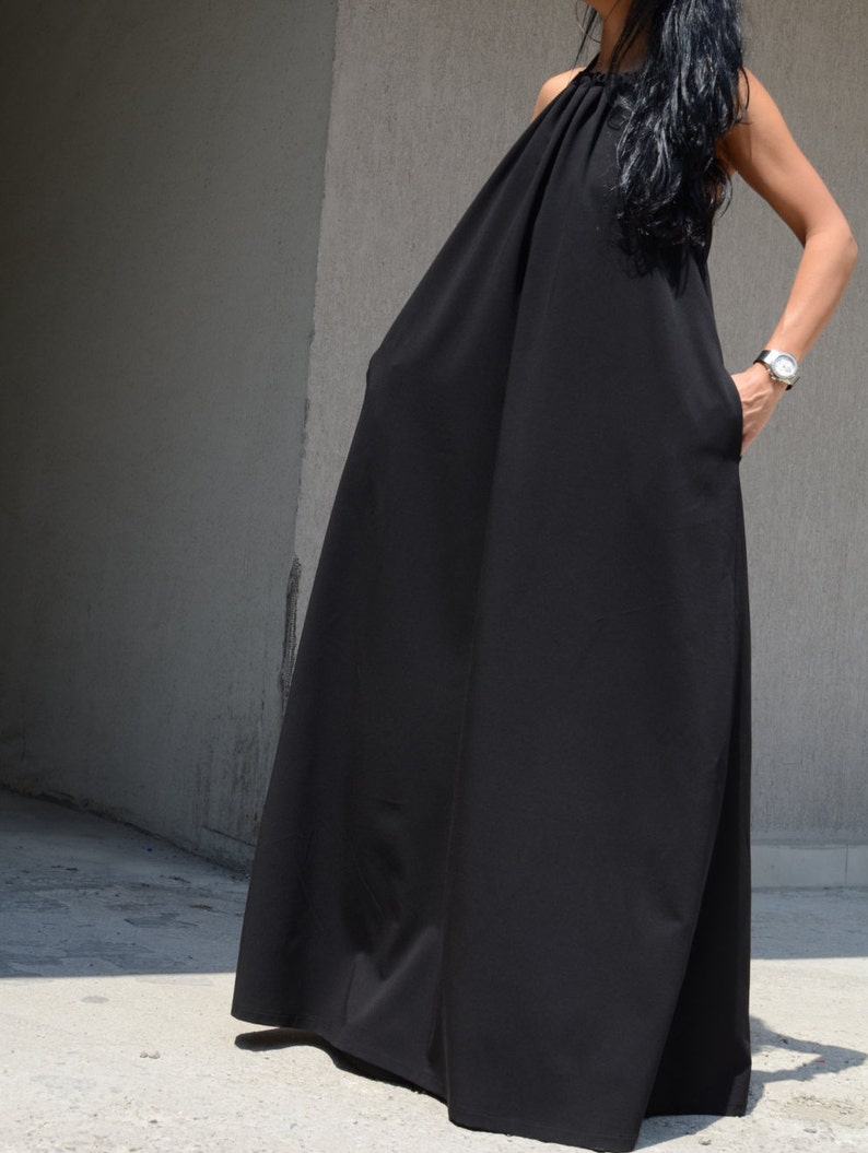 Pu&ograve; includere: Un abito maxi nero con scollo halter e una silhouette ampia e fluida.