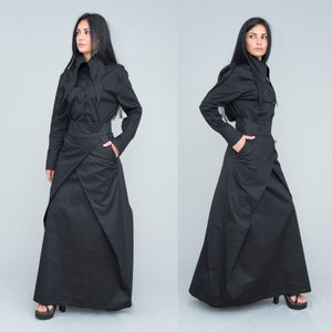 May include: A black long-sleeved shirt with a high collar and a black wrap skirt. The skirt has a unique design with multiple layers and folds.