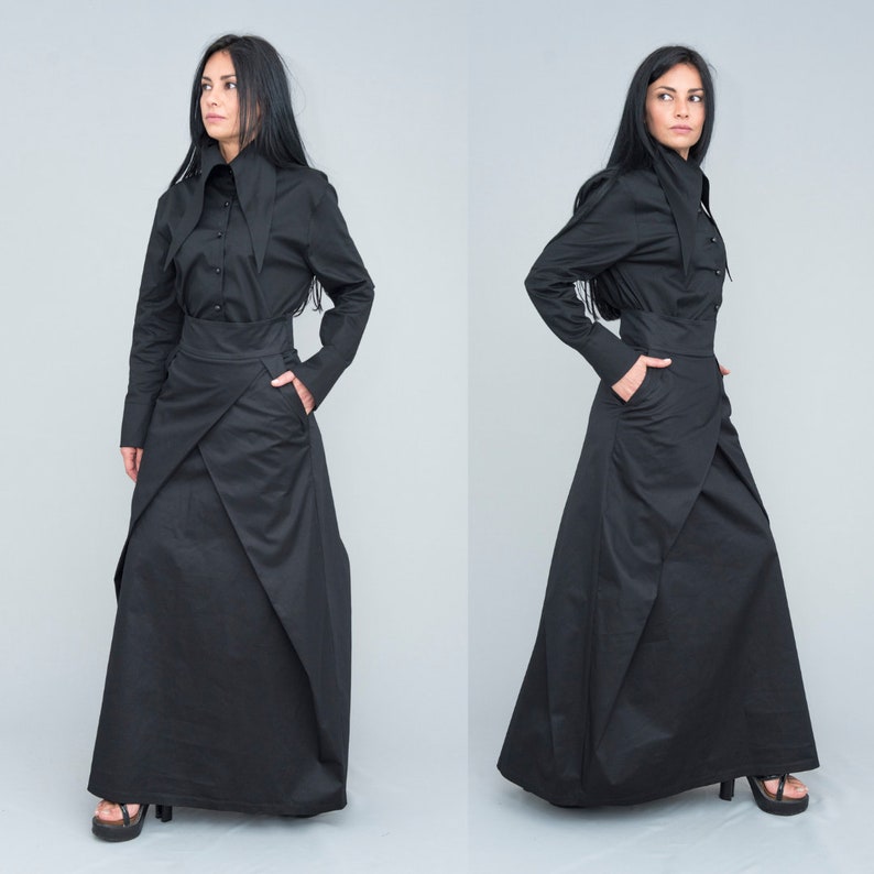 May include: A black long-sleeved shirt with a high collar and a black wrap skirt. The skirt has a unique design with multiple layers and folds.