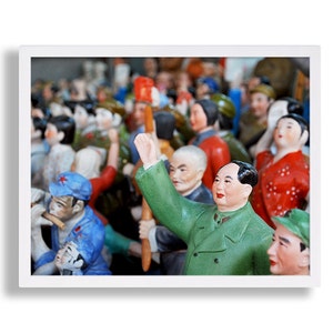 Puede incluir: Impresi&oacute;n enmarcada que presenta una multitud de peque&ntilde;as figuras coloridas. La figura central, con una chaqueta verde, levanta un brazo. Otras figuras visten ropa roja, azul y verde. El fondo est&aacute; borroso, lo que sugiere una gran reuni&oacute;n.