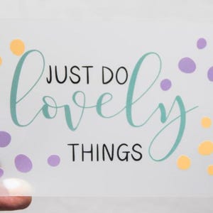 May include: A rectangular translucent sheet featuring the text JUST DO in black, the word lovely in a teal cursive script, and the word THINGS in black. The design is accented with scattered yellow and purple circles of varying sizes.