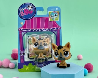 Może przedstawiać: Figurkę hieny w kolorze brązowym i czarnym z linii zabawek Littlest Pet Shop. Figurka jest zapakowana w plastikowe opakowanie blister z różowym i fioletowym tłem. Opakowanie zawiera logo Littlest Pet Shop i tekst "A4333 4+".
