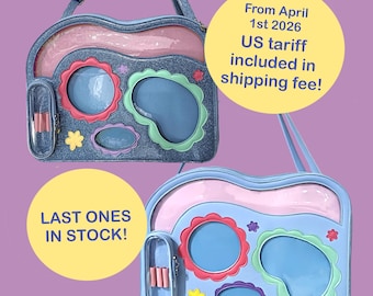 May include: Two blue and pink decorative bags with clear window pockets and floral accents. One bag has the text "LAST ONES IN STOCK!" and the other has the text "From April 1st 2026 US tariff included in shipping fee!"