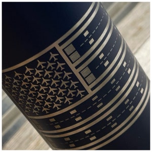 May include: A navy blue water bottle with a silver graphic design. The design features a pattern of airplanes and runways, resembling a flag. The bottle is cylindrical and appears to be made of metal.