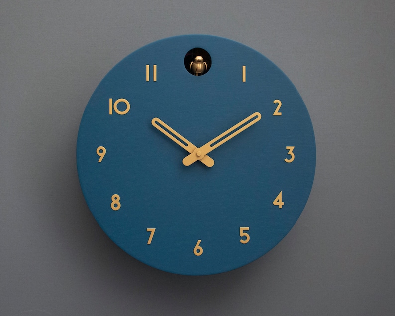 May include: A blue round clock with gold hands and gold numbers. The clock has a cuckoo bird on the top.