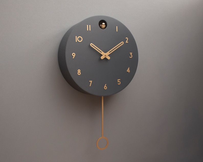 May include: A black pendulum clock with gold-coloured hands and numbers. The clock has a simple design and a minimalist aesthetic.