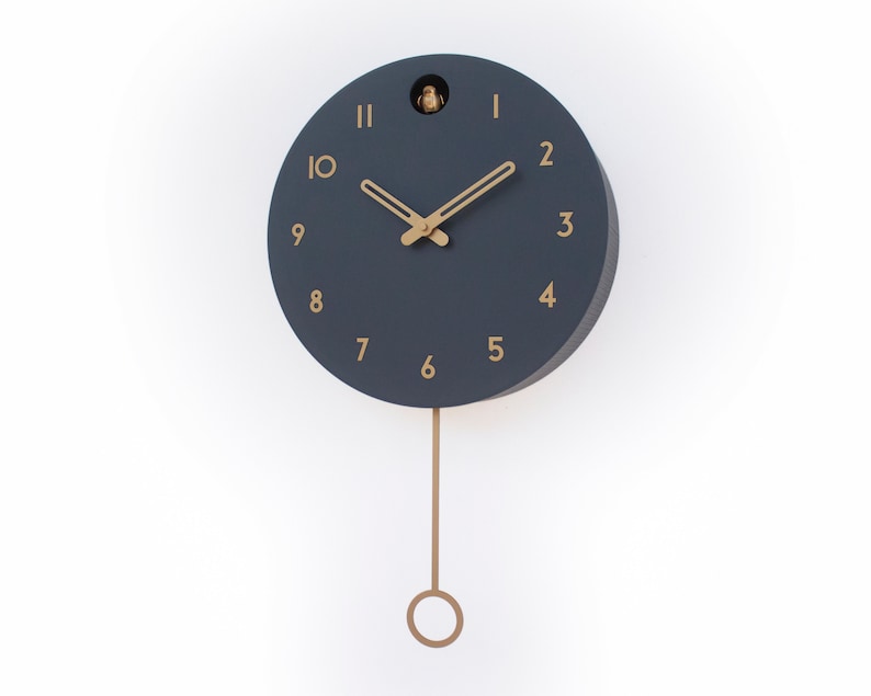 May include: A dark blue round clock with gold accents and a pendulum. The clock face has Roman numerals and a cuckoo bird at the top.