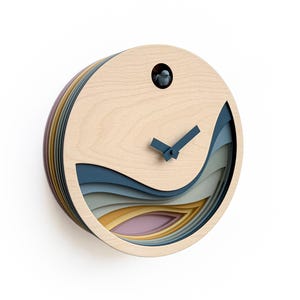 K&ouml;nnte beinhalten: Eine runde Holzkuckucksuhr mit einem geschichteten Design mit blauen, grauen, gelben und rosa Wellen. Die Uhr hat schwarze Zeiger und einen kleinen Vogel in der Mitte.