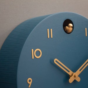 May include: A blue wooden cuckoo clock with gold hands and Roman numeral markings. The clock has a small bird cutout on the top.