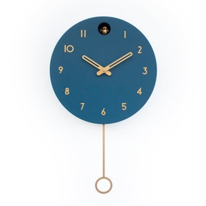 May include: A blue round clock with gold hands and numbers. The clock has a pendulum and a small bird cutout at the top.