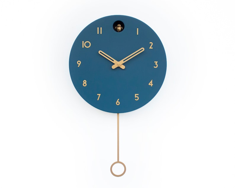 May include: A blue round clock with gold hands and numbers. The clock has a pendulum and a small bird cutout at the top.