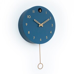 May include: A blue round cuckoo clock with gold-colored hands and numbers. The clock has a pendulum and a small bird cutout on the face.