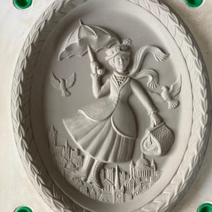 Könnte beinhalten: Eine Keramikform einer Frau, die einen Regenschirm und eine Handtasche hält und durch eine Stadt mit Vögeln, die um sie herum fliegen, geht. Die Form ist in hellgrau gehalten und hat ein detailliertes Design.