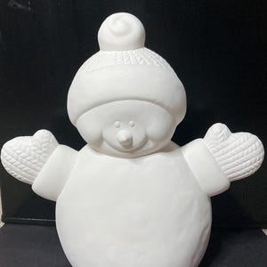 Può includere: Statuetta di pupazzo di neve in ceramica non verniciata, pronta per la personalizzazione. Il pupazzo di neve indossa un cappello e dei guanti, con un corpo rotondo e un viso sorridente. La statuetta è alta circa 20 cm.