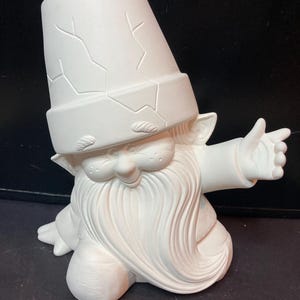 May include: A white ceramic garden gnome figurine with a large, cracked pot for a hat. The gnome has a long, flowing beard, a smiling face, and is gesturing with one hand. The figurine is unpainted and ready for customization.