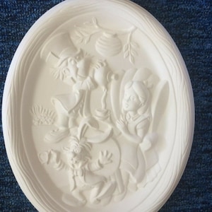 May include: White ceramic oval plate with a raised design of Alice in Wonderland characters, including the Mad Hatter, the March Hare, and Alice. The characters are depicted in a whimsical scene, with the Mad Hatter holding a teapot and the March Hare holding a watch.