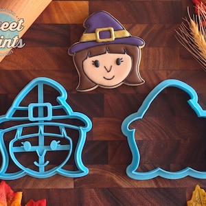 May include: A light blue plastic cookie cutter shaped like a witch with a hat, a matching light blue outline cutter, and a decorated sugar cookie featuring a brown-haired witch wearing a purple hat with a gold buckle and a black outline.