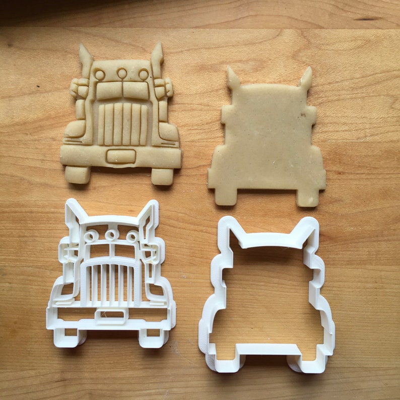 May include: Two cookie cutters in the shape of a semi-truck. One is white plastic and the other is made of brown dough.