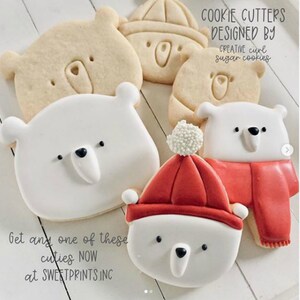 May include: Set of five cookie cutters featuring polar bear designs. The cutters include a polar bear wearing a red hat, a polar bear with a scarf, and three different polar bear faces. The text "COOKIE CUTTERS DESIGNED BY CREATIVE curl sugar cookies" is visible in the image.