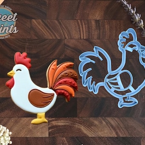 May include: A rooster-shaped cookie decorated with white icing, a red comb and wattle, a brown wing, and a multi-colored tail in shades of orange and brown, alongside a light blue plastic rooster-shaped cookie cutter with a detailed outline.