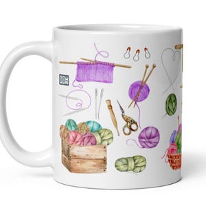 May include: White ceramic mug with a colorful illustration of knitting supplies, including yarn balls, needles, and a wooden box. The illustration is in a watercolor style.